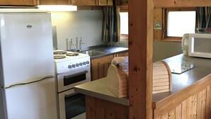 A kitchen with wooden cabinets, a stove, an oven, a sink, and a microwave. - Conifer Chalet 5 - UKC5219 (Crieff)
