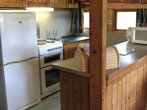 A kitchen with wooden cabinets, a stove, an oven, a sink, and a microwave. - Conifer Chalet 5 - UKC5219 (Crieff)