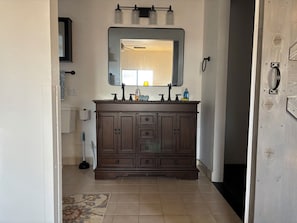 Un baño con tocador de madera oscura, un espejo grande y una lámpara sobre el espejo.
