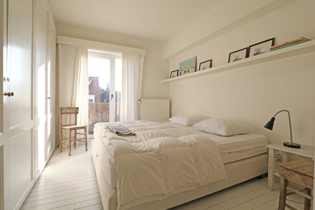 Ein Schlafzimmer mit einem Bett, einem Sessel, einem Schreibtisch und einer Heizung.