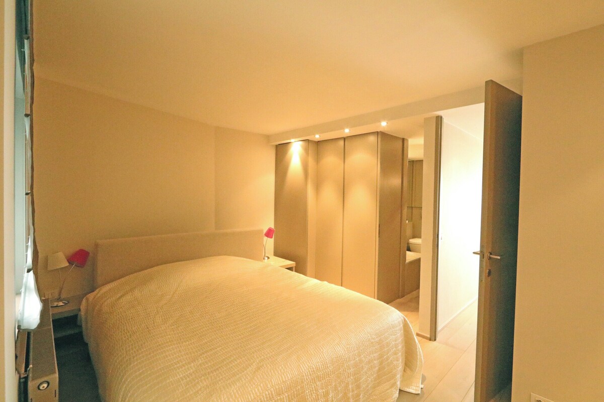 Ein Hotelzimmer mit einem großen Bett, einem Nachttisch mit Lampe und einem Kleiderschrank.