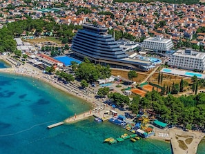 Eine Luftaufnahme einer Küstenregion mit einem großen Hotel, einem Strand und einer Marina.
