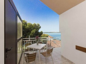 A balcony with a table and chairs, a view of the sea, and a white railing. - Apartment in Brodarica by Sandy Beach (Sibenik)