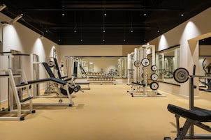Un gimnasio con diversos equipos de ejercicio, incluyendo máquinas de pesas, pesas libres y máquinas de cardio.