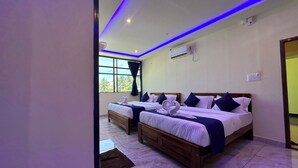 Une chambre d’hôtel avec deux lits, une grande fenêtre et un plafond doté d’un éclairage LED bleu.