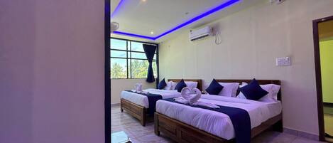 Habitación de hotel con dos camas, un ventanal grande e iluminación LED azul en el techo.