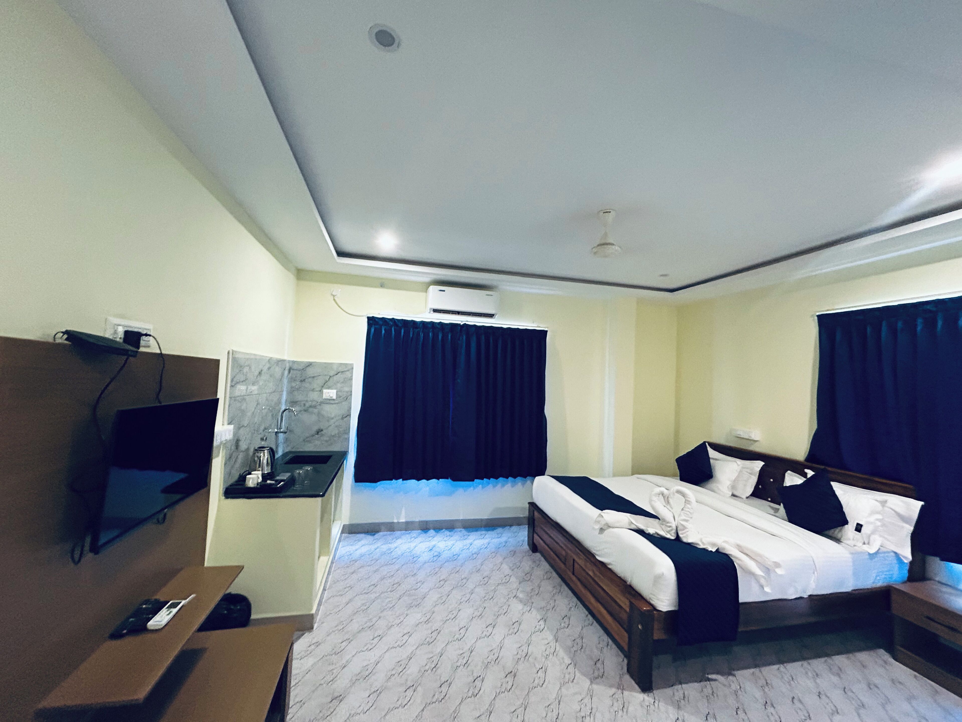 Una habitación de hotel con cama, mesita de noche, escritorio y televisor.