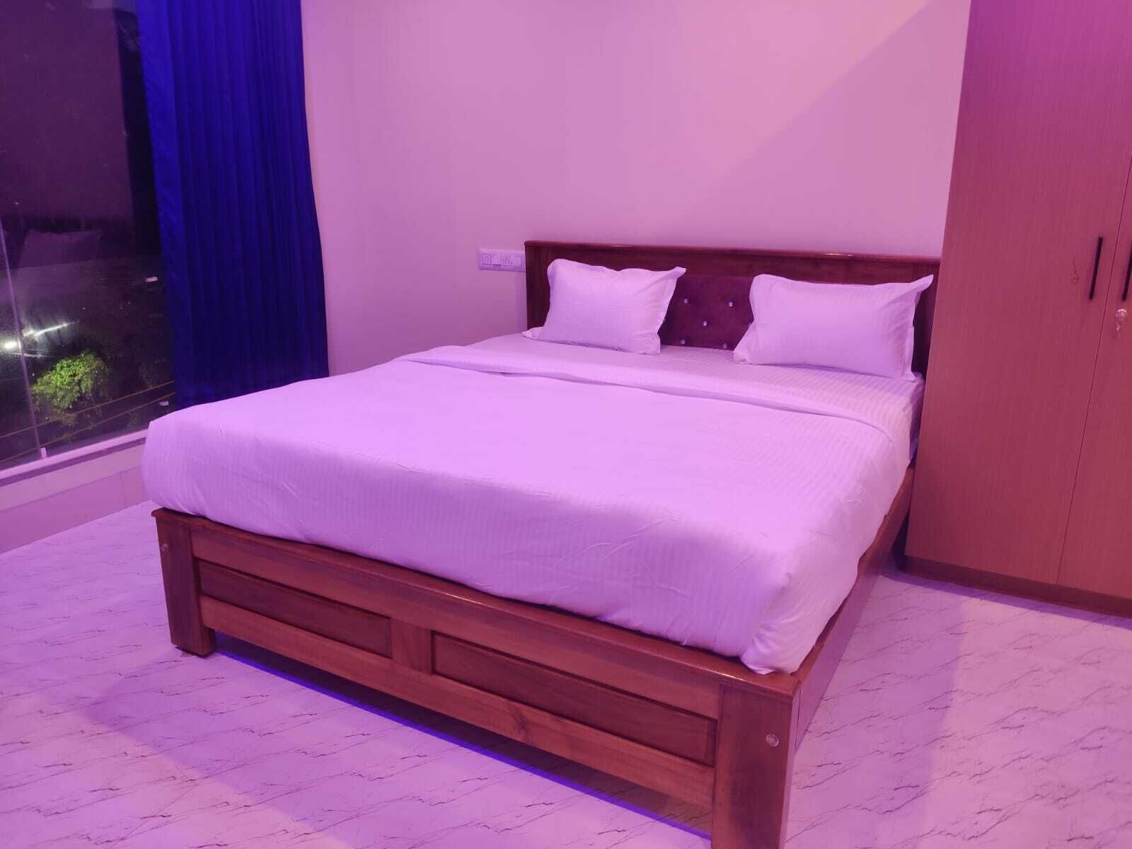Una cama de madera con ropa de cama blanca en una habitación con ventana y armario.