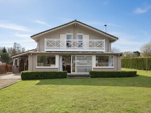Ein zweistöckiges Haus mit Balkon, überdachter Veranda und gepflegtem Rasen.