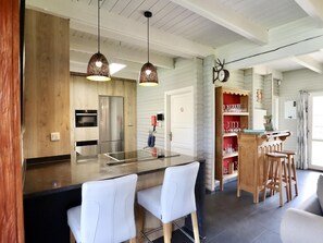 Eine moderne Küche mit Kochinsel, Pendelleuchten und einer Holzbar.