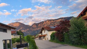 Une rue résidentielle bordée de maisons, avec une chaussée asphaltée et des montagnes en arrière-plan.