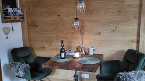 Une pièce aux murs lambrés, avec deux chaises, une table et des luminaires suspendus.