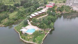 Uma ilha com piscina, alguns edifícios e uma grande extensão de água.
