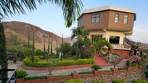 Um edifício moderno de dois andares com fachada de pedra, um caminho de tijolos vermelhos e uma escadaria que leva à entrada.