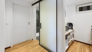Ein modernes Interieur mit einer Schiebetür, Holzböden und einer Küchenzeile inklusive Kaffeemaschine.