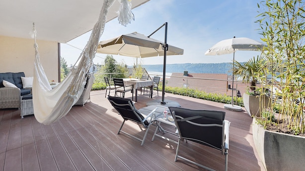Eine Terrasse mit Gartenmöbeln, einer Hängematte und Sonnenschirmen.