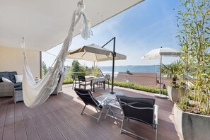 A patio with outdoor furniture, a hanging chair, and umbrellas. - Premium Apartment – Above the Rooftops of Sipplingen with Panoramic Lake View & Private Terrace (Sipplingen)