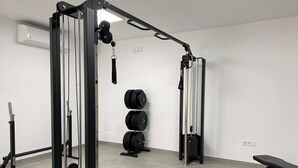 Uma academia com suporte para agachamento, barra, anilhas e um banco.