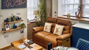 Una sala acogedora con un sofá de cuero marrón, una mesa de centro de madera y un comedor con platos y tazas.