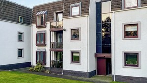 Un edificio residencial moderno de varios pisos, con balcones, ventanas amplias y techo plano.