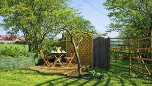 A patio with a table and chairs, surrounded by a wooden fence and greenery. - 1 bedroom accommodation in Langley (Langley)
