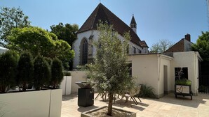 En innergård med en kyrka, en planteringslåda med ett träd och en planteringslåda med växter.