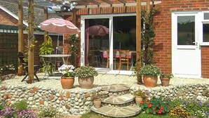 A patio with a table and chairs, a pergola, and potted plants. - 1 bedroom accommodation in Weybourne (Weybourne)
