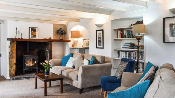 A cozy living room with a fireplace, sofas, a coffee table, and a bookshelf. - 4 bedroom accommodation in St. Teath (St. Teath)
