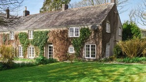 A traditional stone house with a sloped roof, multiple windows, and ivy growth on the walls. - 4 bedroom accommodation in St. Teath (St. Teath)