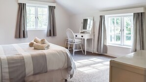 A bedroom with a bed, a desk, a chair, a dresser, and a hanging light fixture. - 4 bedroom accommodation in St. Teath (St. Teath)