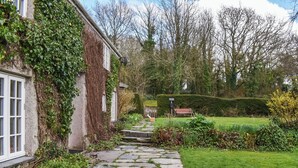 A stone pathway leading to a house with ivy-covered walls and a well-maintained lawn. - 4 bedroom accommodation in St. Teath (St. Teath)