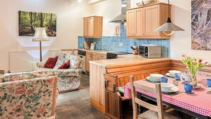 Una cocina acogedora con armarios de madera, una mesa de comedor con mantel a cuadros y un sofá con tapicería floral.