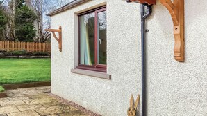 Ein Haus mit Fenster, Holzbalken und einem Steinweg.