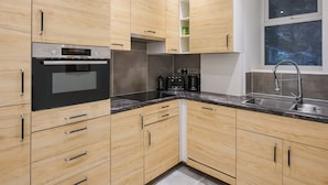 Una cocina moderna con armarios de madera, horno Bosch, encimera negra y ventana con vistas.