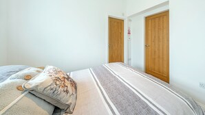 A bedroom with a bed, a pillow, and two wooden doors.