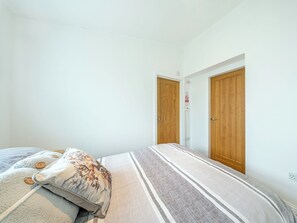 A bedroom with a bed, a pillow, and two wooden doors.