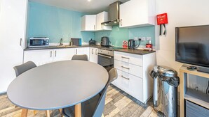 A compact kitchen with a dining area, a microwave, a coffee maker, and a TV.