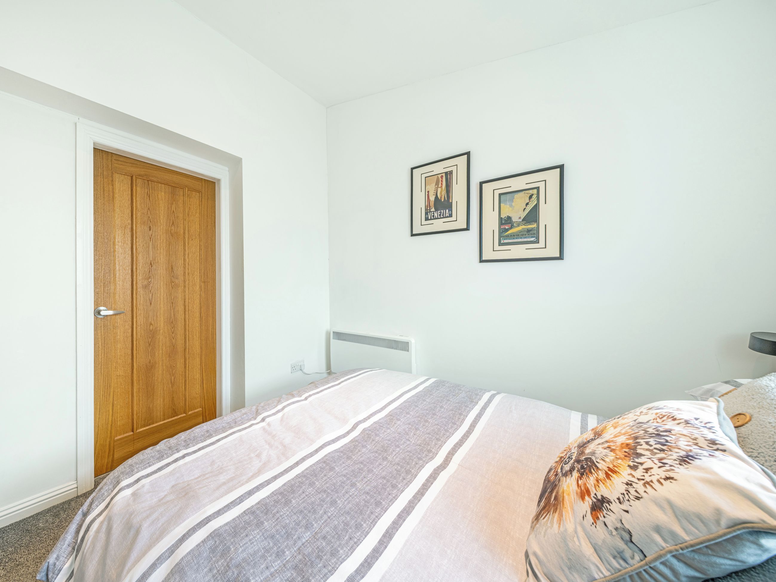 Ein Schlafzimmer mit einem Bett, einer Holztür und zwei gerahmten Bildern an der Wand.