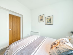 Una camera da letto con un letto, una porta in legno e due quadri appesi al muro.