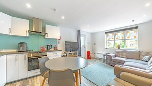 A modern kitchen with a dining area, a sofa, and a TV.