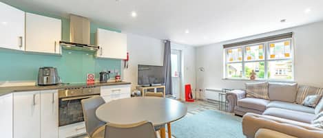 Ett modernt kök med en matplats, en soffa och en tv.