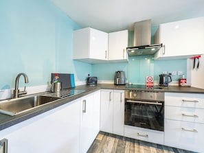 Una cucina moderna con mobili bianchi, elettrodomestici in acciaio inossidabile e una parete blu.
