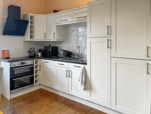 Une cuisine avec des meubles blancs, une cuisinière, un four et un four à micro-ondes.