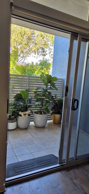 A sliding glass door leading to a patio with potted plants and a view of trees and a fence. - A perfect place to hide away with river side charm (Balmoral)