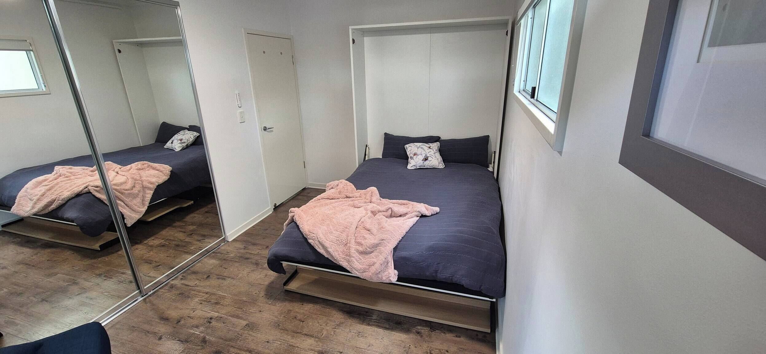 A bedroom with two beds, a large mirror, and a window.