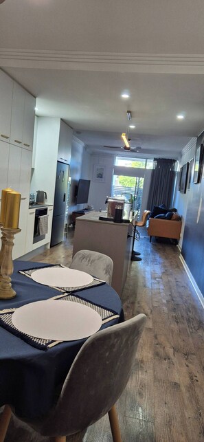 A modern kitchen with white cabinets, a built-in oven, and a dining area with a table set for two. - A perfect place to hide away with river side charm (Balmoral)