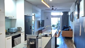 A modern kitchen with a dining area, a sofa, and a view of the city.