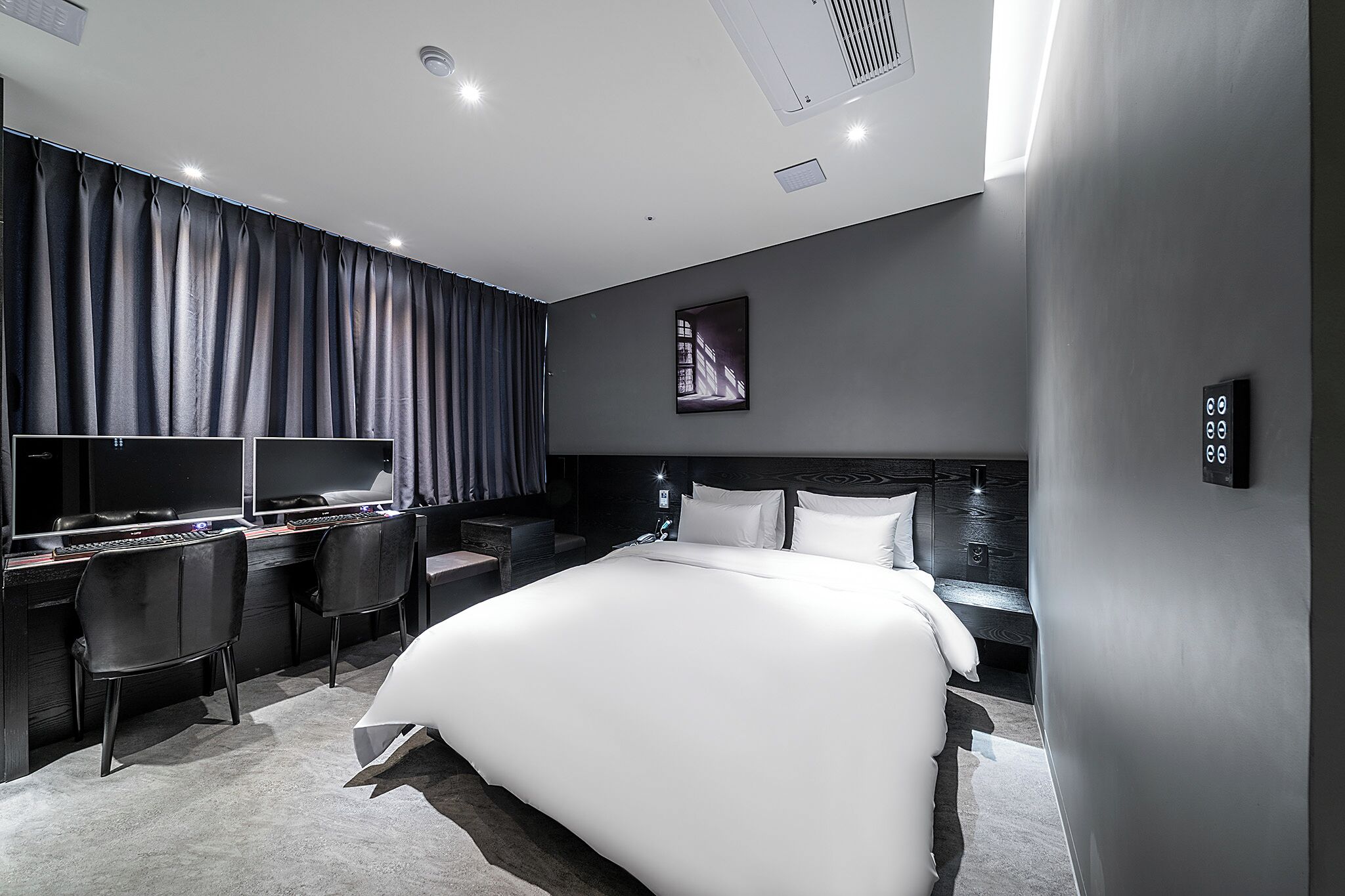 Habitación de hotel moderna con una cama grande, un escritorio con ordenador y una silla.
