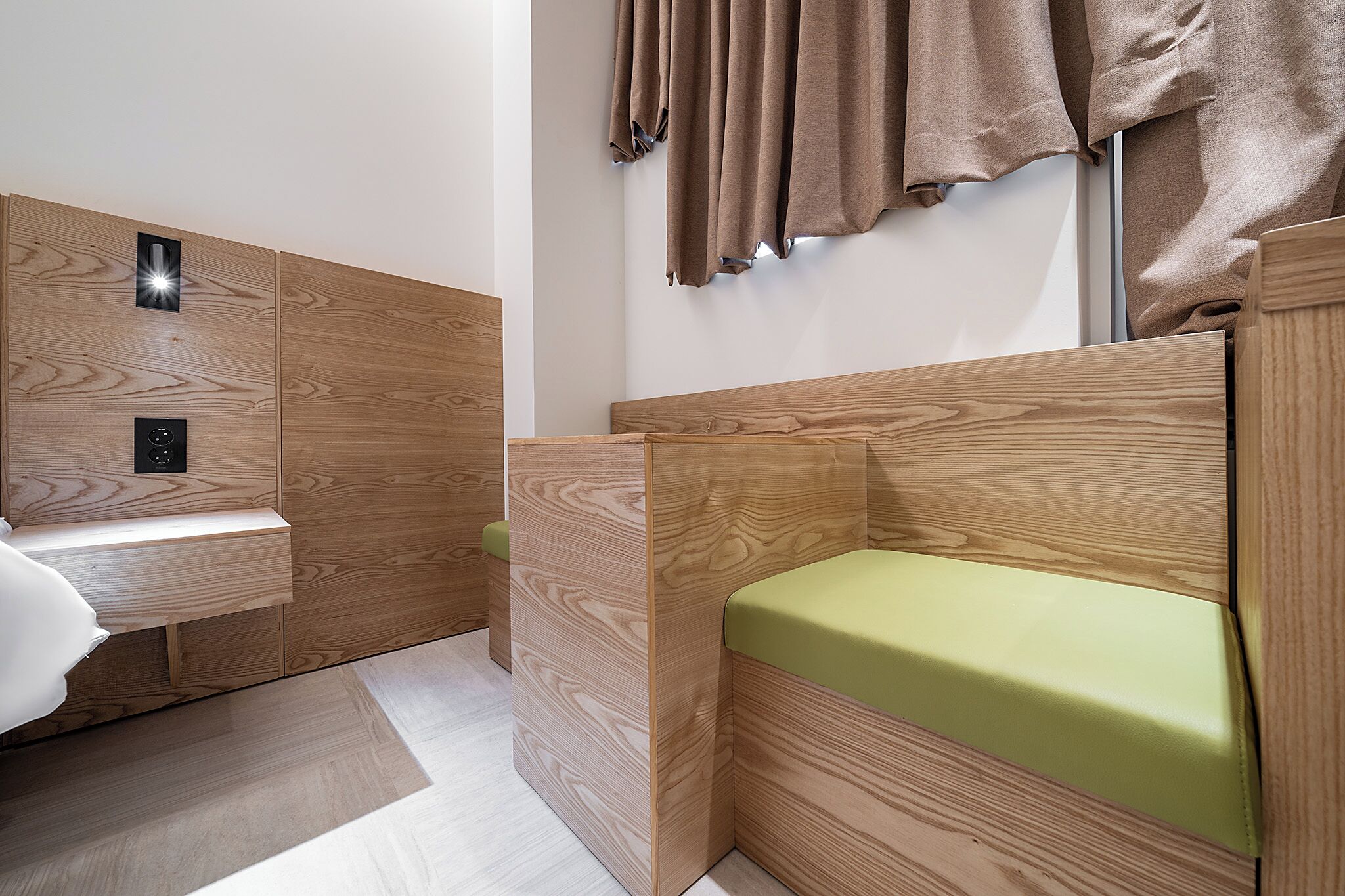 A modern room with a wooden headboard, a bedside table, and a green cushion.