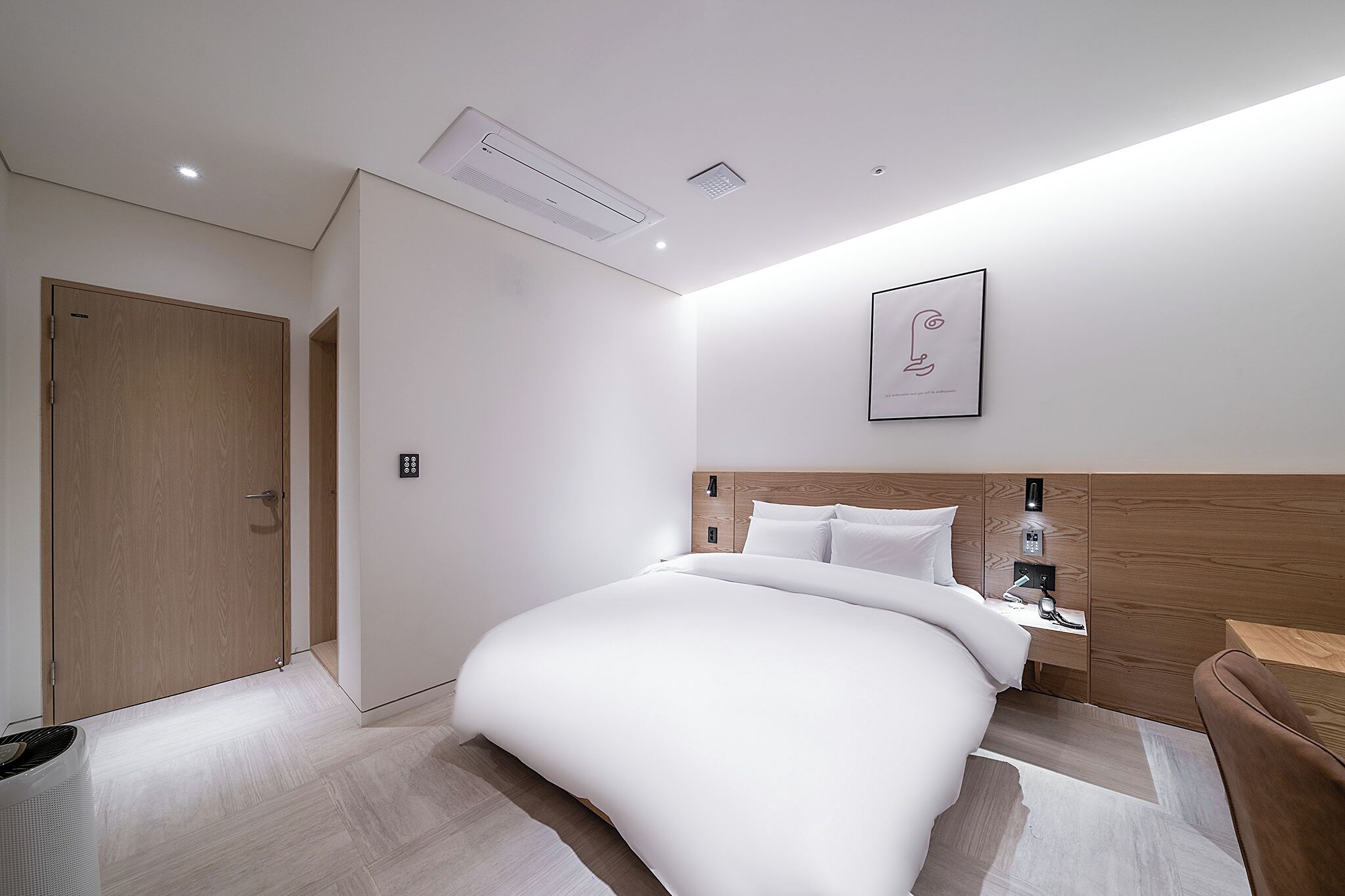 Una habitación de hotel moderna con una cama grande, una mesita de noche y una obra de arte colgada en la pared.